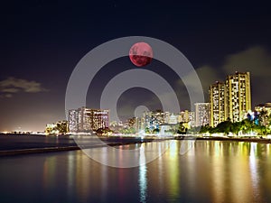 Large pink moon over the skies of Waikiki Beach Honolulu Hawaii Island USA