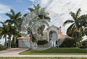 Large pink and yellow tropical house with circular driveway.