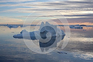 A large pinnacled iceberg floats and melts in a fjord in northwest Greenland