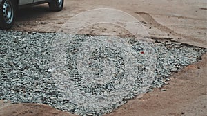Large pit in asphalt road covered with rubble. Concept of problem roads.