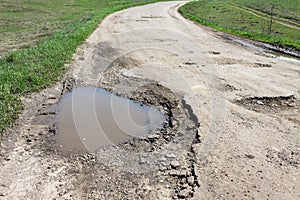 large pit on the road filled with water, the concept of bad broken roads, maintenance and repair of the road