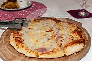 Large pizza with cheese on a round wooden tray