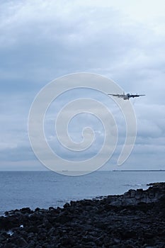 a large plane flying over the ocean towards land in front of the water: Jeju, Korea