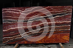 A large plate of natural stone of red color with beautiful stripes is called Onice Fantastico photo