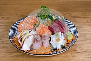 Large plate of sashimi, raw and fresh sliced fish served with vegetables