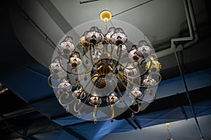 Large pompous classic chandelier in a basement loft interior. Eclecticism in interior design