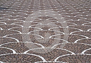 Large porphyry paving with semicircular decorative motifs in white stone cubes