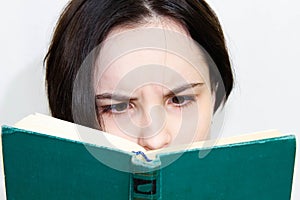 Large portrait of a beautiful girl with a surprised face, reading an old book. Bibliophile