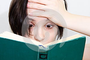 Large portrait of a beautiful girl with a surprised face, reading an old book. Bibliophile