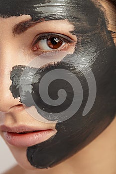 It is large portrait of girl with black clay mask.