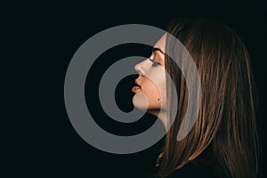 Large portrait of the girl`s profile. Girl`s face on a black background. Beautiful girl sad