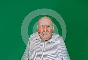 a large portrait of an old man with a serious look on an isolated green background.