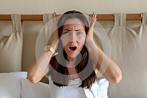 Large portrait of a woman holding her head with her hands, the concept of headache, migraines, noisy neighbors, roommates make noi