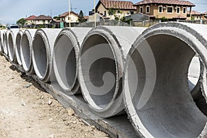 Large Precast concrete pipesegments prepared on a road for sewage, storm drain or water supply project near a residential area