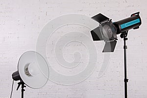 Large professional photo studio lamps on a white brick wall