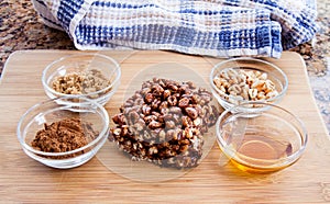 Large puffed wheat square treat with small glass bowls of raw ingredients beside