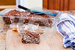 Large puffed wheat square treat with small glass bowls of raw ingredients beside