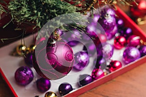 A large purple decorated Christmas ball on a branch of a New Year`s Eve against the background of other colored decorations