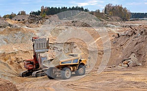 Large quarry dump truck. The excavator loading of a stone in the dump truck. Loading sand. Mining equipment for the transportation