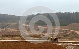 Large quarry dump truck. View of the large sand pit. Production useful minerals.