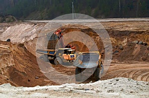 Large quarry dump truck. View of the large sand pit. Production useful minerals