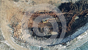 Large quarry site with an excavating vehicle in a top view. Heavy industrial equipment working.