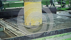 A large radio-controlled machine fills the concrete in form. Workers in the workshop of the House-building plant