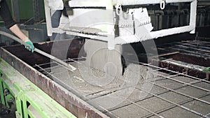 A large radio-controlled machine fills the concrete in form. Workers in the workshop of the House-building plant