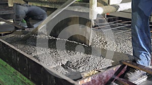 A large radio-controlled machine fills the concrete in form. Workers in the workshop of the House-building plant