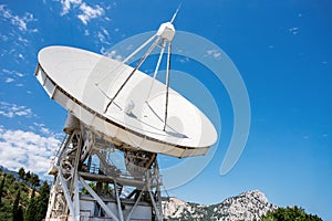 Large radio telescope near mountains at daytime