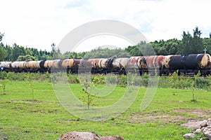 A large railway train with many tank cars carries goods by rail. Rail transportation of liquid cargo