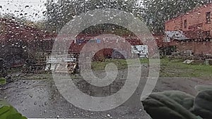 Large rain drops strike a window pane during a summer shower