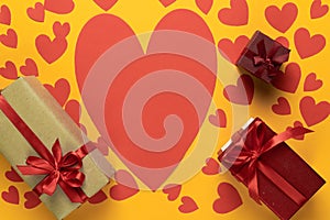 Large red cardboard heart on a yellow background. Many different gift boxes. St. Valentine's Day