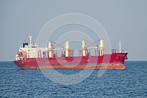 Large red cargo ship sailing in open sea