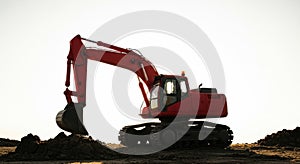 Red excavator working on a construction site against a bright sky