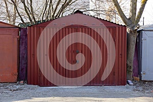 Large red metal garage with closed gates standing outside