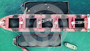 Large red Mother Vessel / Loading coal on bulk vessel ship in offshore cargo port. Aerial top view.