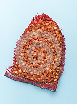 A large red net with onion seeds on a blue background