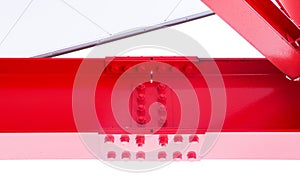 Large red screw hexagon flange nut supporting structures, metal frame of prefabricated building on white background.