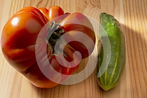 Large red tomato and cucumber on a wooden background