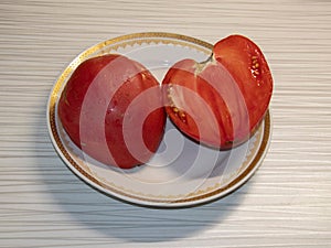 A large red tomato, cut in half, on a plate.