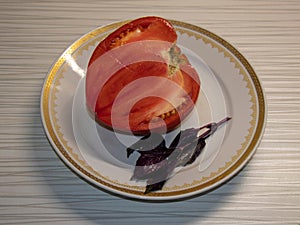 A large red tomato, cut in half, on a plate.