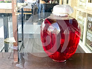 A large red transparent glass round luminous bright jar, the capacity of a delicious sweet juice, a hamper, a mors, wine, liquid s