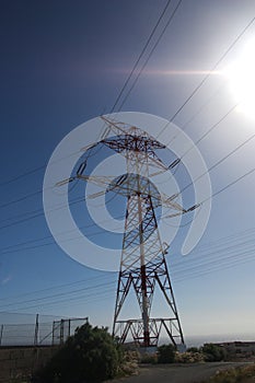 A large red and white tower with high voltage from the ground