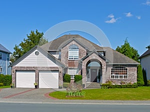 Large residential house with concrete driveway on blue sky background