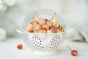 large ripe pink cherries in a white colander