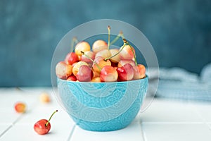 large ripe yellow pink cherries in a blue bowl