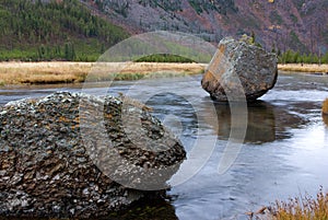 Large rock boulder rests in the flowing river horizontal landscape view