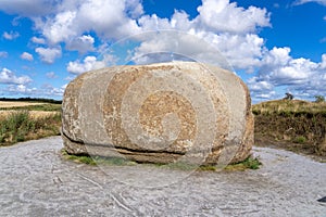 Large rock formation on a gravel road beneath a cloudy blue sky in Nationalpark Thy, Denmark.
