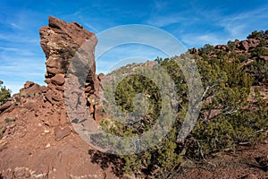 Large rock formation poking up from a mountainside with brush